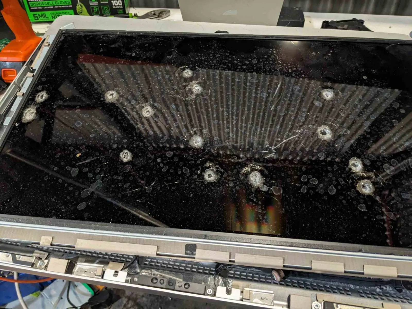 Damaged Apple iMac with visible bullet holes on the aluminum chassis